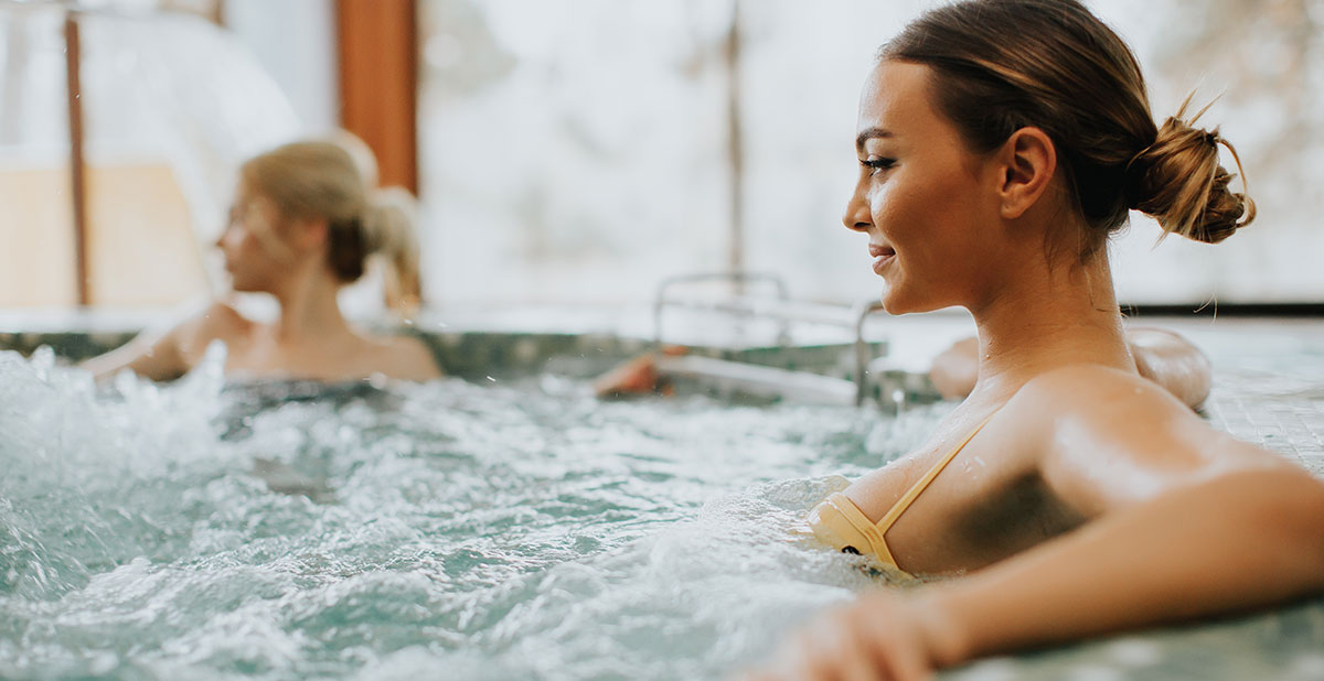 Two women in a hot tub with one of them smiling.