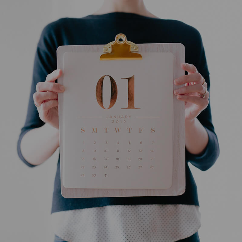 A person holding an empty calendar in front of their face.